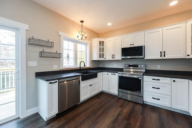 kitchen with sink, hanging light fixtures, appliances with stainless steel finishes, and white cabinets