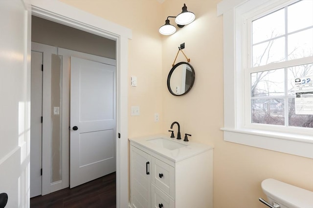 bathroom with toilet, vanity, wood-type flooring, and plenty of natural light