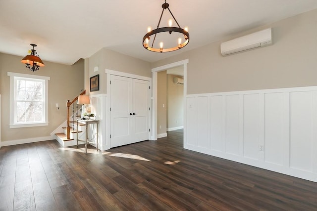 spare room with a wall unit AC, a chandelier, and dark hardwood / wood-style flooring