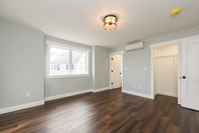 unfurnished bedroom featuring a wall unit AC, a closet, and dark hardwood / wood-style floors