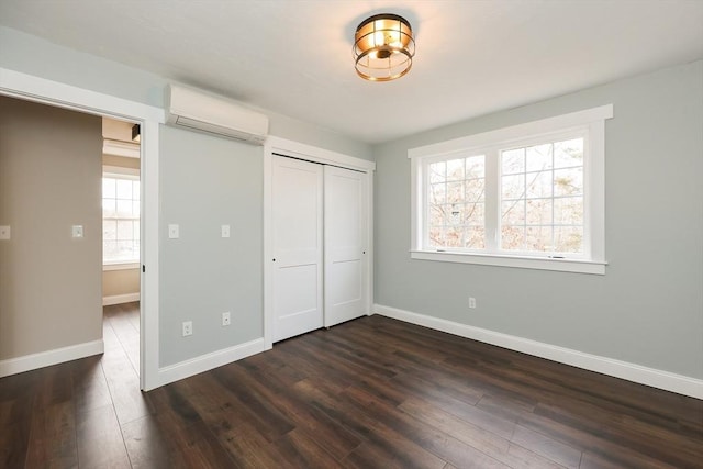 unfurnished bedroom featuring a closet, dark hardwood / wood-style flooring, and a wall mounted air conditioner