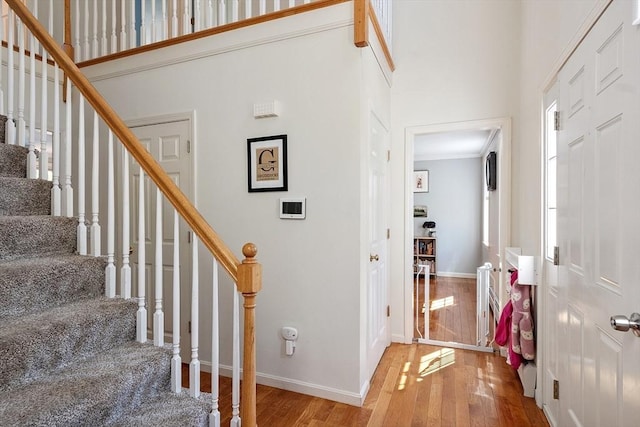 foyer entrance with wood-type flooring, stairway, a high ceiling, and baseboards