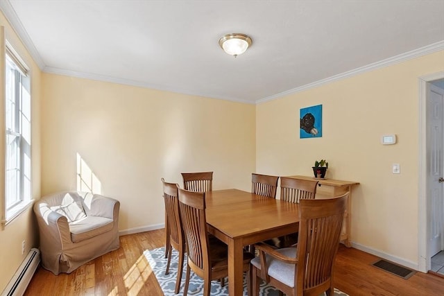 dining area featuring baseboard heating, healthy amount of natural light, light wood finished floors, ornamental molding, and baseboards