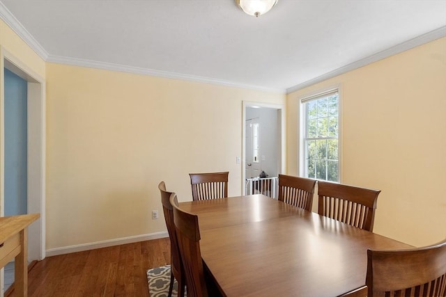 dining room with crown molding, wood finished floors, and baseboards