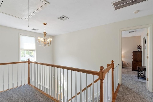 hallway featuring attic access, an upstairs landing, and carpet floors