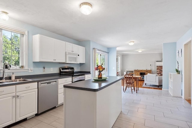kitchen featuring appliances with stainless steel finishes, a sink, dark countertops, and a kitchen island