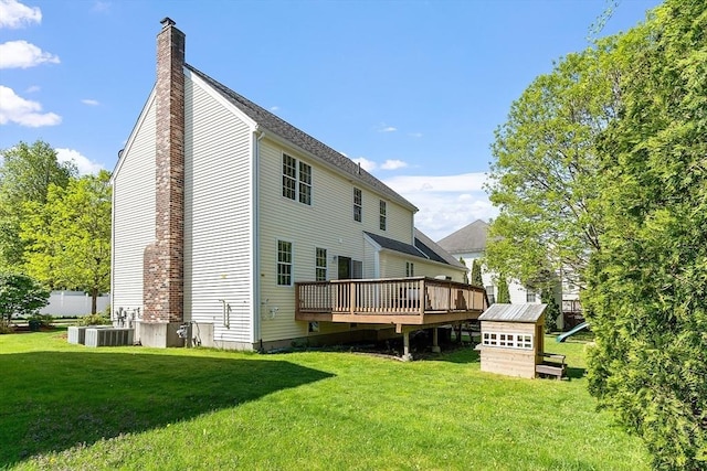 back of property featuring a chimney, a lawn, a wooden deck, and a storage unit