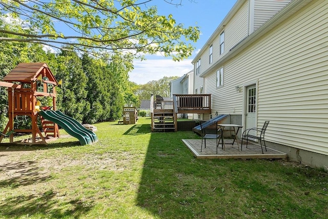 view of green lawn with a playground, a deck, and a patio area