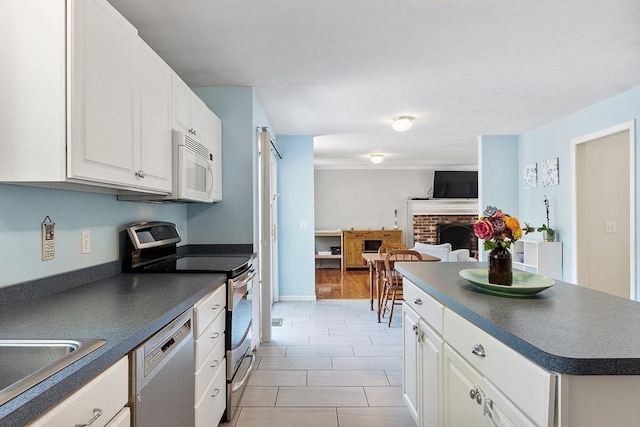 kitchen featuring stainless steel appliances, dark countertops, white cabinetry, and a sink