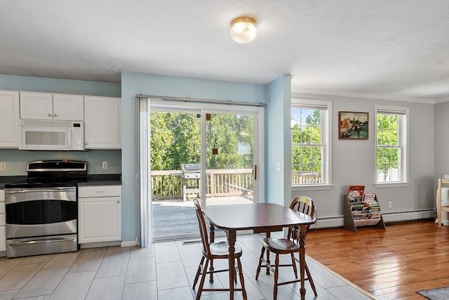 kitchen with white microwave, stainless steel electric stove, white cabinetry, light wood-type flooring, and crown molding