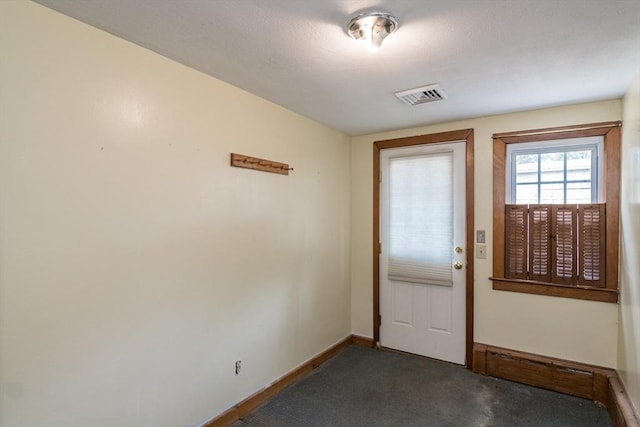 interior space featuring baseboards, visible vents, and dark carpet