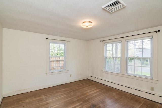 spare room with a baseboard radiator, visible vents, baseboards, and wood-type flooring