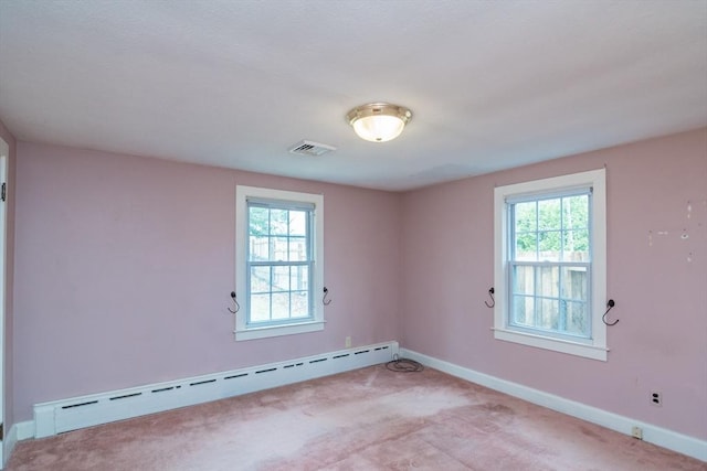empty room featuring plenty of natural light, baseboard heating, and light carpet