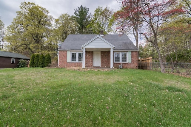 view of front of house with a chimney, brick siding, fence, and a front lawn