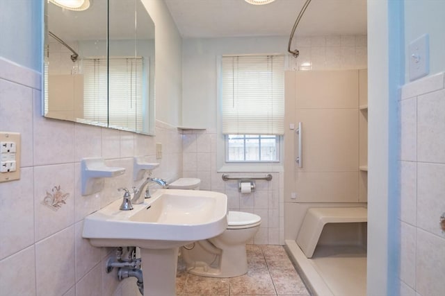 bathroom featuring toilet, tile walls, a shower, and tile patterned flooring
