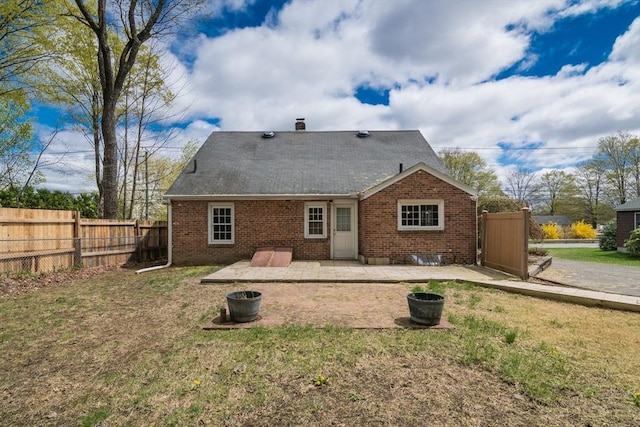 back of house featuring a patio, a lawn, brick siding, and fence