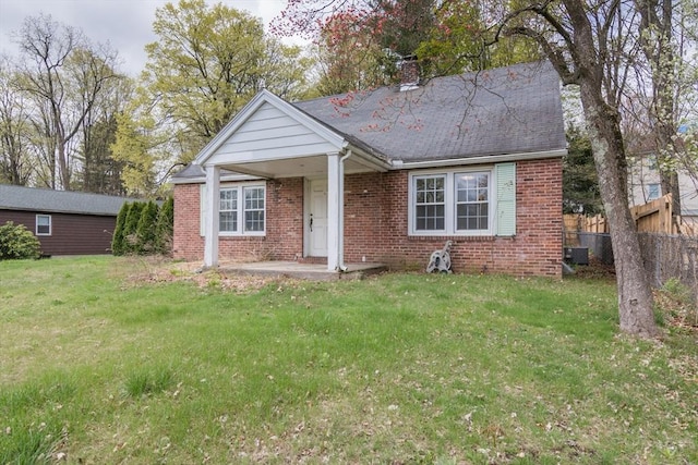 view of front of house with a chimney, brick siding, fence, and a front yard