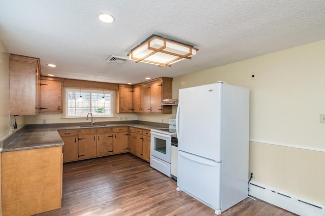 kitchen with a sink, dark countertops, visible vents, a baseboard heating unit, and white appliances