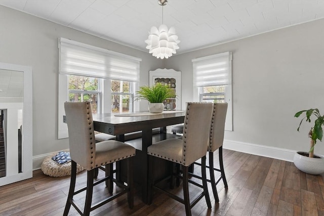 dining space with baseboards, hardwood / wood-style flooring, and a chandelier