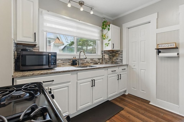 kitchen featuring a sink, decorative backsplash, stainless steel microwave, and black range with gas stovetop