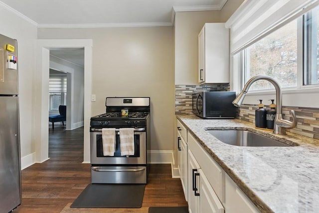 kitchen with a sink, dark wood-style flooring, appliances with stainless steel finishes, and ornamental molding