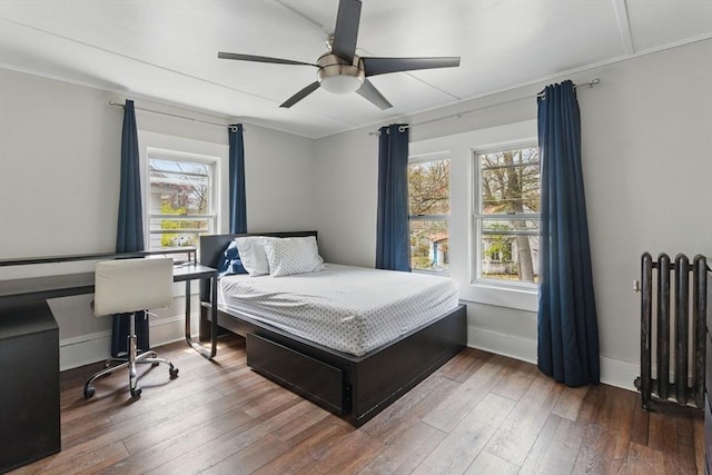 bedroom featuring wood-type flooring, a ceiling fan, radiator, and baseboards