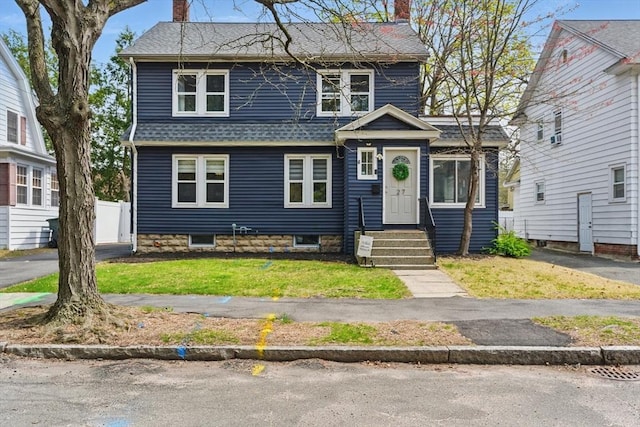 view of front of home featuring roof with shingles, fence, a front yard, and a chimney