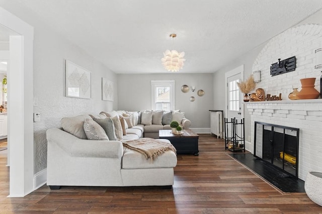 living area featuring baseboards, a brick fireplace, and wood finished floors