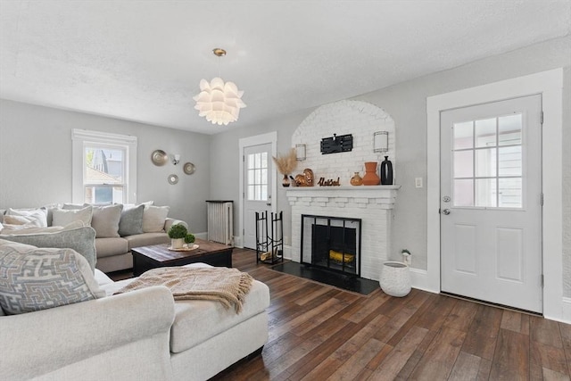 living area with a fireplace, baseboards, radiator heating unit, and dark wood-type flooring