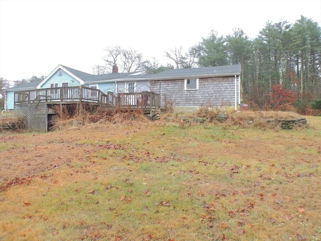 rear view of property featuring a lawn and a wooden deck