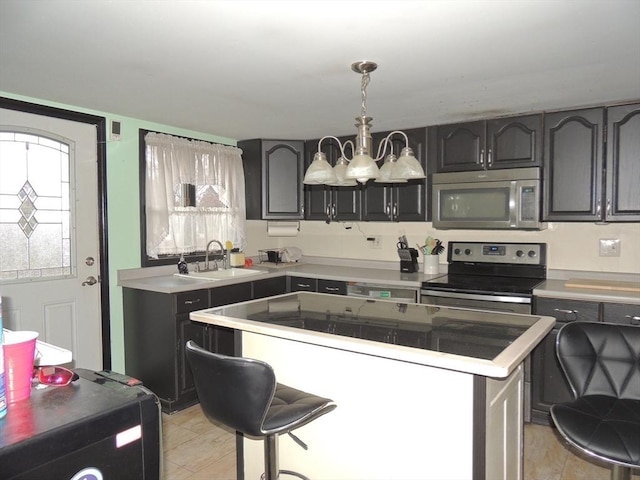 kitchen with appliances with stainless steel finishes, sink, an inviting chandelier, a center island, and a breakfast bar area