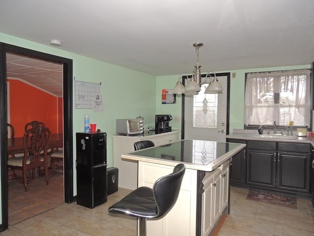 kitchen with a center island, sink, hanging light fixtures, a notable chandelier, and white cabinets