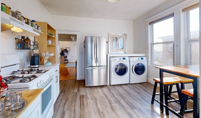 kitchen with light hardwood / wood-style floors, gas range gas stove, white cabinetry, stainless steel fridge, and washing machine and dryer