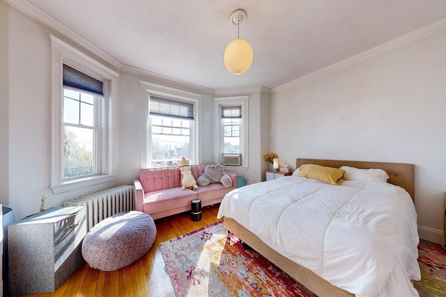 bedroom with wood-type flooring, crown molding, and radiator heating unit