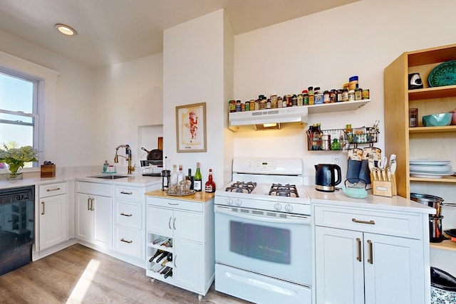 kitchen with white range with gas cooktop, sink, exhaust hood, and white cabinets