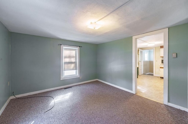 carpeted spare room featuring a textured ceiling