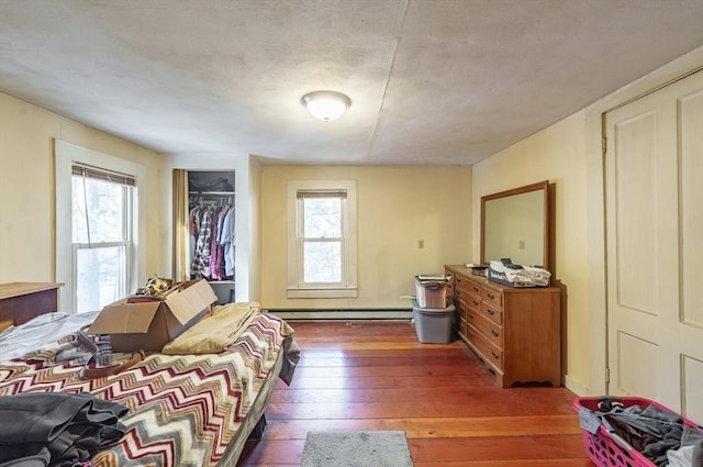 bedroom featuring dark hardwood / wood-style flooring, a baseboard radiator, and a closet