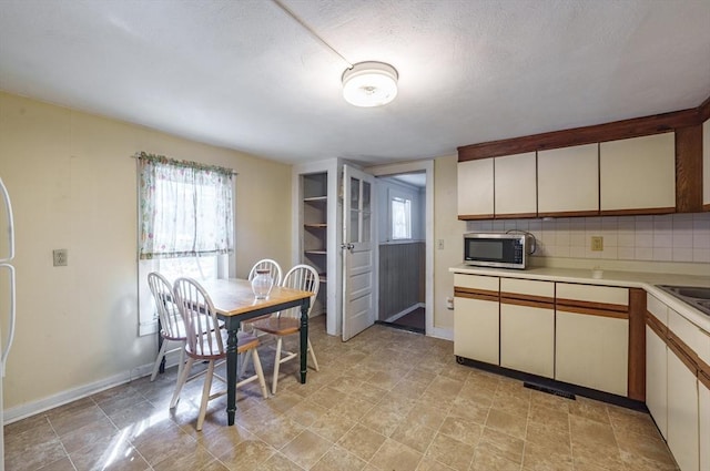 kitchen featuring white cabinets, backsplash, and a textured ceiling