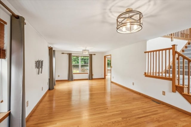 unfurnished living room featuring light hardwood / wood-style flooring and an inviting chandelier