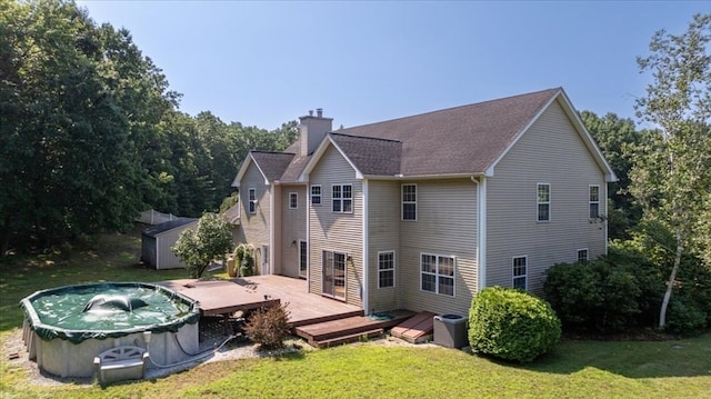 back of house with central AC unit, a shed, a deck, and a lawn