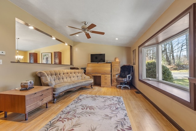 living room featuring ceiling fan with notable chandelier, vaulted ceiling with beams, and light hardwood / wood-style floors