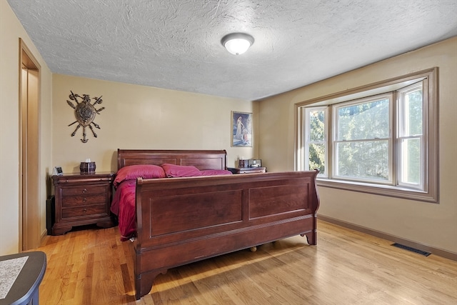 bedroom with a textured ceiling and light hardwood / wood-style flooring