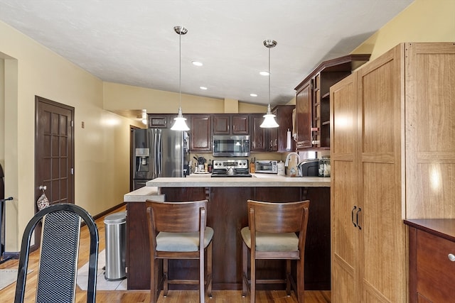 kitchen with lofted ceiling, hanging light fixtures, light hardwood / wood-style floors, dark brown cabinetry, and stainless steel appliances