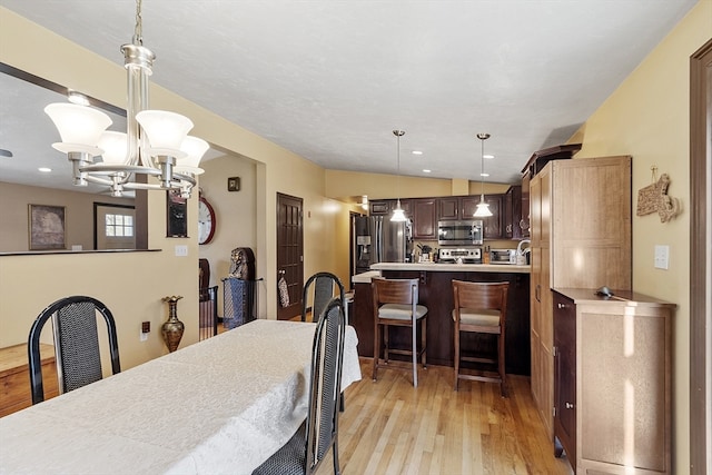 dining area featuring light hardwood / wood-style flooring, vaulted ceiling, and a notable chandelier