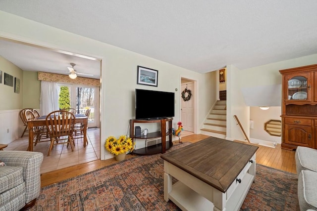 living room featuring stairs, a ceiling fan, and dark wood-type flooring