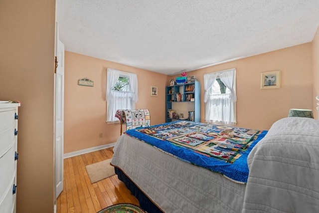 bedroom featuring baseboards, a textured ceiling, and light wood finished floors