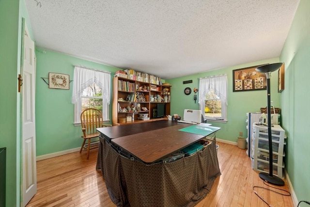 office space featuring a textured ceiling, light wood-style floors, and a healthy amount of sunlight