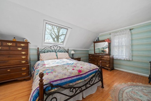 bedroom with light wood finished floors, wallpapered walls, baseboards, and lofted ceiling