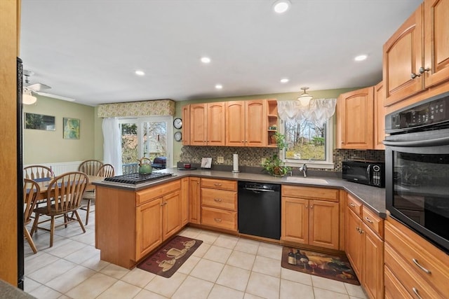 kitchen with black appliances, backsplash, a healthy amount of sunlight, and a peninsula