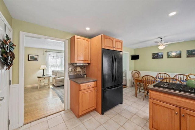 kitchen featuring dark countertops, wainscoting, light tile patterned flooring, ceiling fan, and freestanding refrigerator